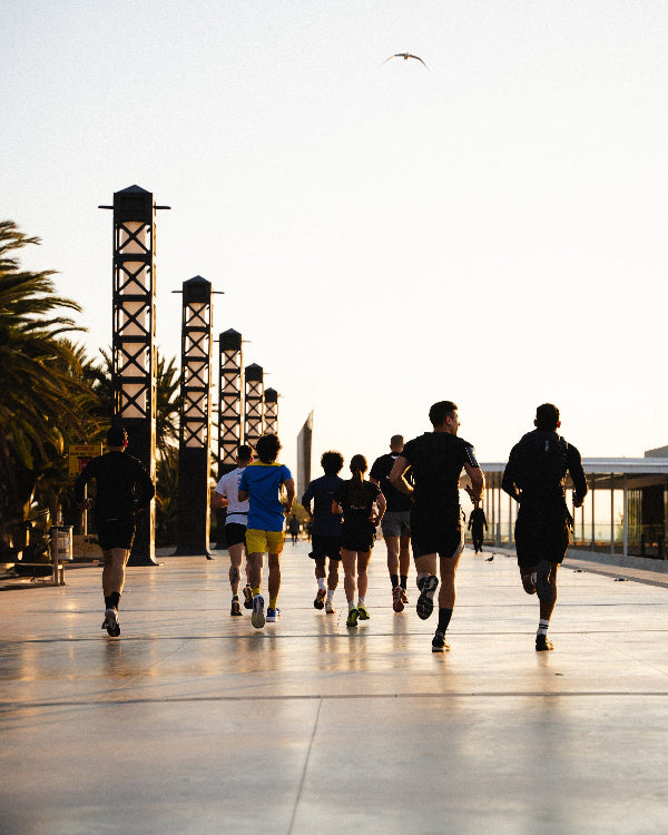 Group of runners on a path with modern architecture and palm trees in the background